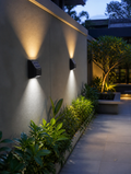 SolarFlux Outdoor Wall Sconce on a garden wall at dusk