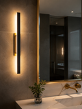 Black and gold LED wall sconce beside bathroom mirror
