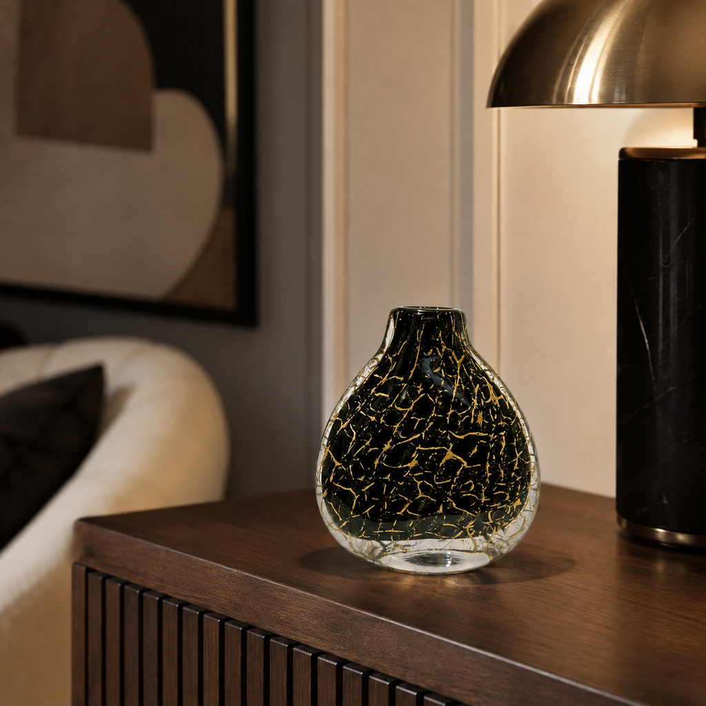 Black and gold hand-blown glass vase on a walnut cabinet