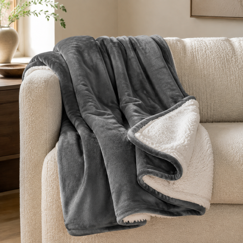 Gray plush sherpa throw blanket draped over a cream sofa