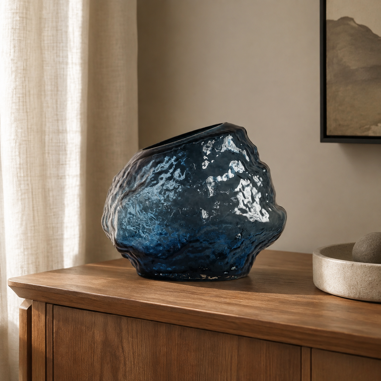 Rock-textured smoky blue glass vase on a walnut console